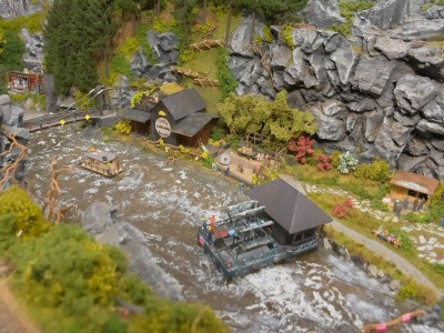 Reissender Fluss mit Wassermühle und Floss sowie Imbiss am Ufer
